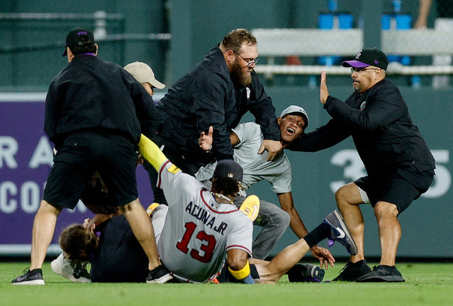A fan charges at Atlanta Braves right fielder Ronald Acuna Jr. (13) as grounds crew detains another person in the seventh inning against the Colorado Rockies at Coors Field in Denver, Colorado on Monday, August 28, 2023. (Photo by Isaiah J. Downing/USA TODAY Sports)