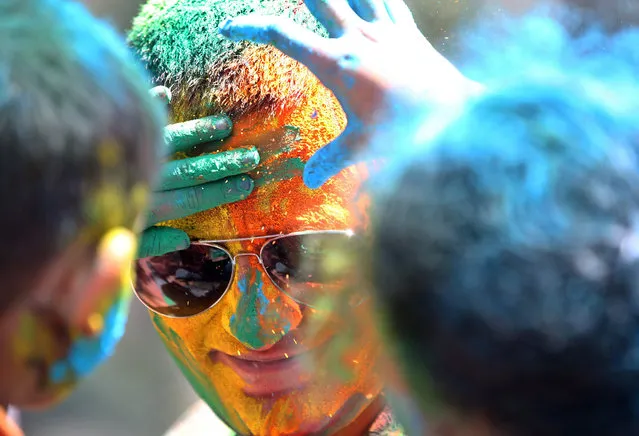 Children smear the face of a man with coloured powder during celebrations marking Holi, the Hindu festival of colors, in Mumbai, India, Friday, March 6, 2015. Holi, India's joyful and colorful celebration of the arrival of spring along with several religious myths and legends, has long ago ceased to be only a Hindu festival. The streets and lanes across most of India turn into a large playground where people off all faiths throw colored powder and water at each other. (AP Photo/Rajanish Kakade)