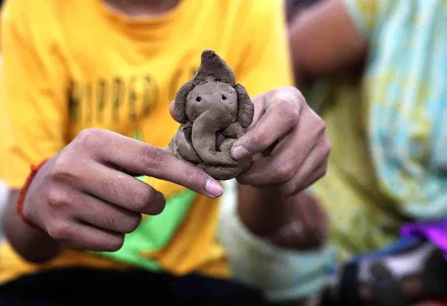 A specially abled boy makes an clay model of elephant-headed Hindu god Ganesha at a camp in Prayagraj, in the northern Indian state of Uttar Pradesh, Friday, September 15, 2023. (Photo by Rajesh Kumar Singh/AP Photo)