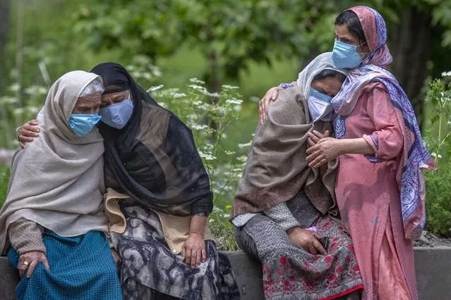 Unidentified women comfort family members of a person who died of COVID-19, at a crematorium in Srinagar, Indian controlled Kashmir, Tuesday, May 25, 2021. India crossed another grim milestone Monday with more than 300,000 people lost to the coronavirus, while a devastating surge of infections appeared to be easing in big cities but was swamping the poorer countryside. (Photo by Dar Yasin/AP Photo)