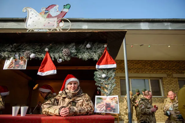 A German Bundeswehr soldier wearing a Christmas hat sits at a hot punch stall at the Christmas market in Camp Marmal in Mazar-e-Sharif, Afghanistan, 22 December 2016. Von der Leyen is in the country for the traditional visit of the minister of defence to German troops at Christmas. (Photo by Gregor Fischer/EPA)