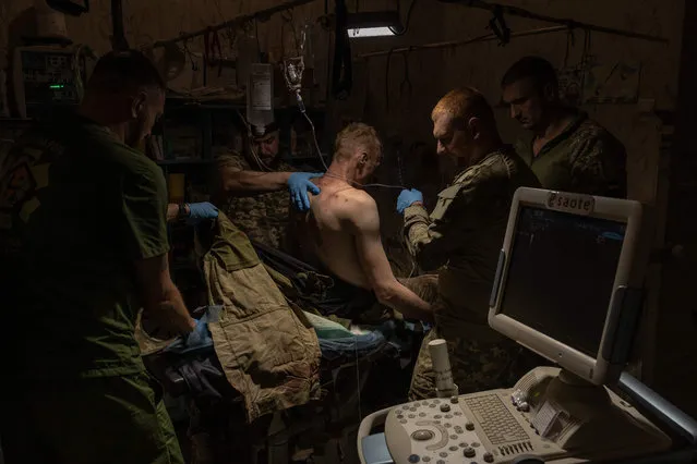 A wounded Ukrainian soldier is treated by Ukrainian military medics in a Ukrainian stabilization point in an undisclosed location near Bakhmut in Ukraine, amid the Russian invasion of Ukraine. (Photo by Roman Pilipey/AFP Photo)