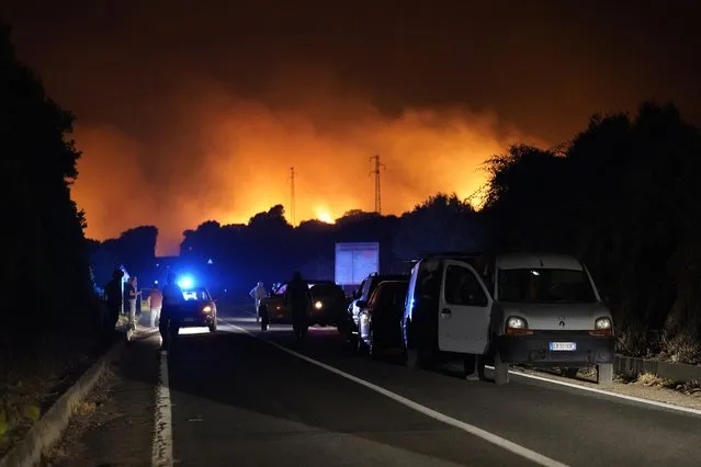Cars are parked by the road as fires have been raging through the countryside in Cuglieri, near Oristano, Sardinia, Italy, early Sunday, July 25, 2021. Hundreds of people were evacuated from their homes in many small towns in the province of Oristano, Sardinia, after raging fires burst in the areas of Montiferru and Bonarcado. (Photo by Alessandro Tocco/LaPresse via AP Photo)