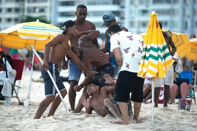 People beat up an unidentified man whom they claim was an alleged pickpocket, on Copacabana beach during New Year's Eve festivities in Rio de Janeiro, Brazil, Monday, December 31, 2018. (Photo by Leo Correa/AP Photo)