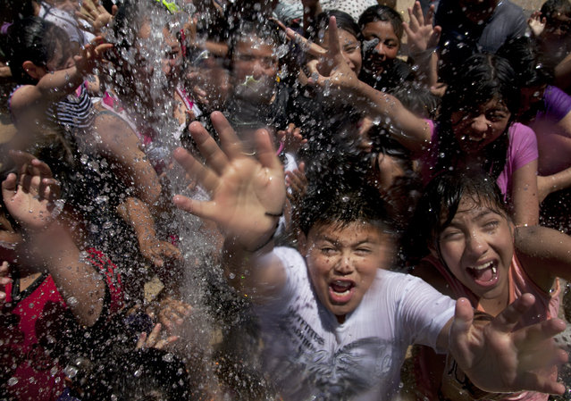 Children frolic in the water fountain of the Revolution Square Monument in Mexico City, Saturday, April 4, 2015. As Holy Week comes to an end, Holy Saturday is a day of mourning for many Mexican Christians as well as a day that is associated with water, representing life and purification. (Photo by Marco Ugarte/AP Photo)