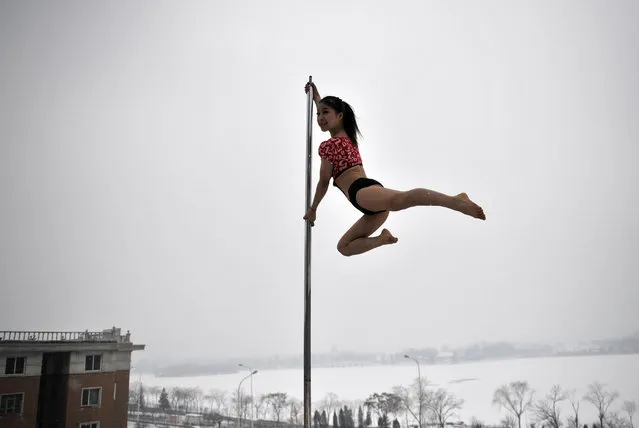 This picture taken on December 17, 2013 shows a pole dancer practising after it snowed in Tianjin during a promotional event by members of China's national pole dancing team and students of the sport. (Photo by AFP Photo)