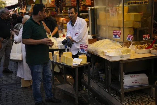 A food shop seller talks to a client in a street market at Eminonu commercial district in Istanbul, Turkey, Wednesday, September 6, 2023. (Photo by Francisco Seco/AP Photo)