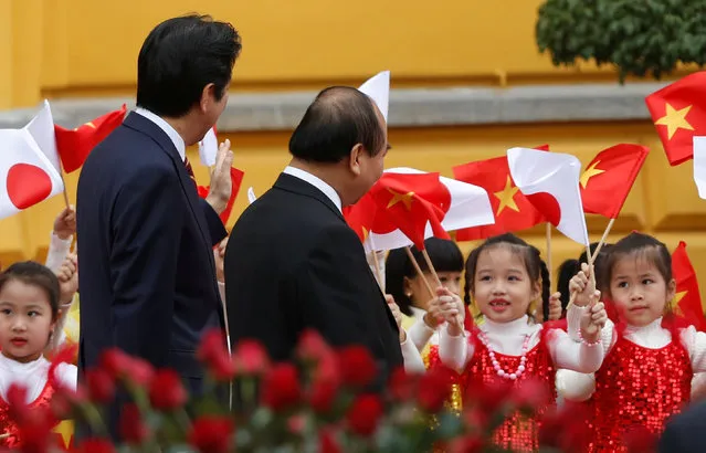 Children wave Vietnamese and Japanese flags to greet Japan's Prime Minister Shinzo Abe (L) and Vietnam's Prime Minister Nguyen Xuan Phuc during a welcoming ceremony at the Presidential Palace in Hanoi, Vietnam January 16, 2017. (Photo by Reuters/Kham)