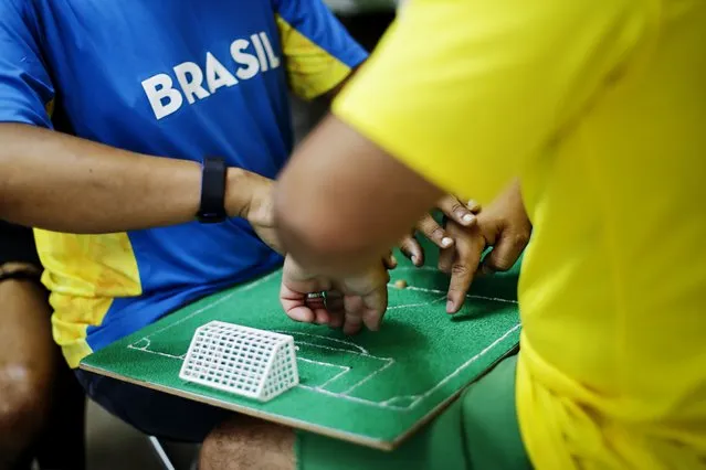 Helio Fonseca, right, helps his deaf and blind friend Carlos Junior with a play-by-play of the World Cup group G soccer match between Brazil and Switzerland, in Osasco, Sao Paulo state, Brazil, Monday, November 28, 2022. Fonseca uses a tactile table and touch on the body of visually and hearing-impaired people to show them the movements of the ball and of the players during soccer matches. Brazil won 1-0. (Photo by Marcelo Chello/AP Photo)