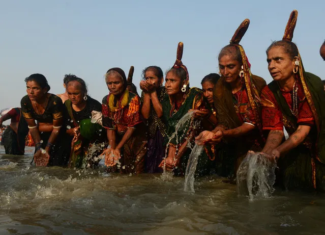 Indian Hindu devotees from a tribal community take a holy bath in the Bay of Bengal and perform rituals at the mouth of the river Ganges on Sagar Island, around 150km south of Kolkata, on January 14, 2017. (Photo by Dibyangshu Sarkar/AFP Photo)