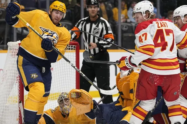 Calgary Flames center Connor Zary (47) hits the puck past Nashville Predators center Yakov Trenin (13) during the first period of an NHL hockey game Thursday, January 4, 2024, in Nashville, Tenn. (Photo by George Walker IVAP Photo)