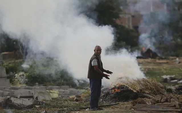 A man stands next to the burning pyre of a family member at a cremation ground in the aftermath of Saturday's earthquake in Bhaktapur, Nepal April 27, 2015. (Photo by Adnan Abidi/Reuters)