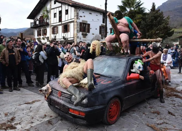 Disguised participants strike poses on a car during the ancient carnival of Ituren, in the northern Spanish Navarra province on January 30, 2017. The yearly three day festivities, revolving mainly around agriculture and principally sheep hearding, run on the last Sunday, Monday and Tuesday of January where Navarra Valley locals from two villages dress up and participate in a variety of activites as they perform a pilgrimage through each village. (Photo by Ander Gillenea/AFP Photo)