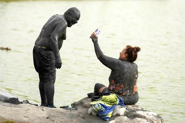 Covered with black mud from head to toe, Manuel Hernandez and his wife Josefina share a light moment on the shore of Las Salinas lagoon in Chilca, Peru, Saturday, February 3, 2024. Las Salinas is a lagoon that is rich in salt and other minerals. (Photo by Martin Mejia/AP Photo)