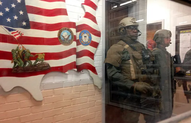 Armed state troopers are seen through a window as they accompany Alabama Gov. Robert Bentley inside Holman prison in Atmore, Ala., on Tuesday, March 15, 2016. Bentley visited the prison in southwest Alabama following two inmate uprisings in four days. Calling the prison archaic, Bentley called on legislators to approve his plan for constructing new prisons. (Photo by Melissa Brown/AP Photo)