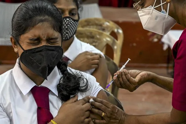 A health worker inoculates a schoolgirl with the dose of Pfizer-BioNTech vaccine against the Covid-19 coronavirus at an educational institution in Colombo on October 26, 2021 in accordance to the directive from the government. (Photo by Ishara S. Kodikara/AFP Photo)