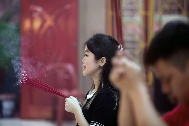 A woman holds incense sticks as she prays during the Lunar New Year celebration at a temple in Medan, North Sumatra, Indonesia, early Saturday, February 10, 2024. Chinese around the globe are celebrating the Lunar New Year that marks the year of the dragon on the Chinese calendar this year. (Photo by Binsar Bakkara/AP Photo)