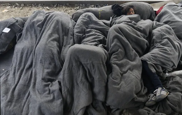 Migrants sleep on train tracks near the makeshift refugee camp at the northern Greek border point of Idomeni, Greece, Monday, March 28, 2016. (Photo by Darko Vojinovic/AP Photo)