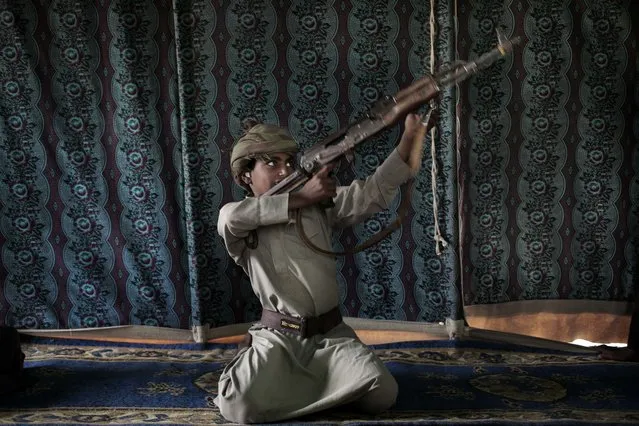 Kahlan, a 12-year-old former child soldier, demonstrates how to use a weapon, at a camp for displaced persons where he took shelter with his family, in Marib, Yemen in this July 27, 2018 photo. Houthi rebels took Kahlan and his classmates, promising to give them new school bags, but instead they were enlisted and trained as fighters tasked with carrying supplies to the front lines. There, he had to elude explosions and airstrikes that left mangled casualties on the battlefield.  “The sight of the bodies was scary”, he said. (Photo by Nariman El-Mofty/AP Photo)