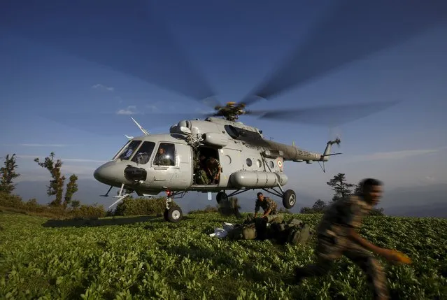 Nepalese army personnel jump out from an Indian helicopter as they unload earthquake relief aid on a hilltop at Dolkha district, Nepal May 14, 2015. (Photo by Navesh Chitrakar/Reuters)