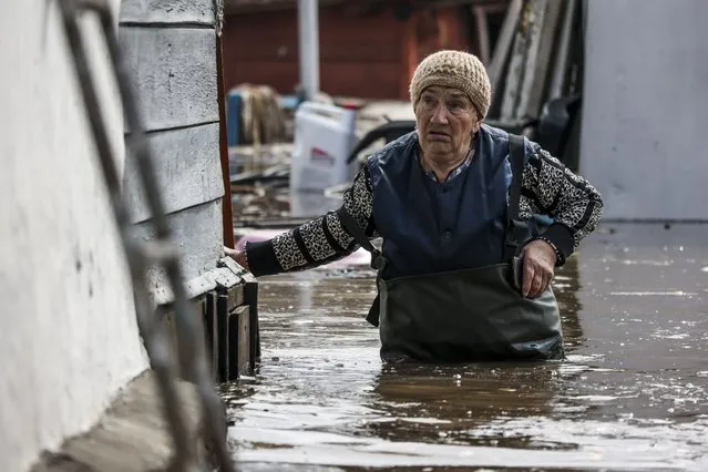 A woman walks near her house in a flooded area in Orenburg, Russia, Wednesday, April 10, 2024. Russian officials are scrambling to help homeowners displaced by floods, as water levels have risen in the Ural River. The floods in the Orenburg region near Russia's border with Kazakhstan sparked the evacuation of thousands of people following the collapse of a dam on Saturday. (Photo by AP Photo)
