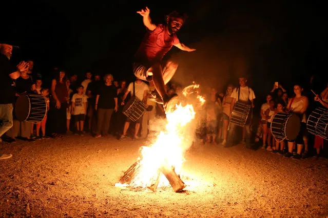 A man jumps over a fire during the annual Klidonas event that takes place on the feast of Saint John the Baptist, in Athens on June 24, 2019. (Photo by Costas Baltas/Reuters)