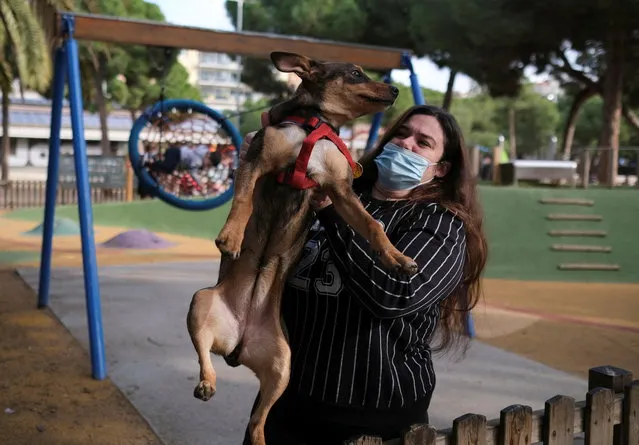 Raquel holds her relative dog Nala, four month old, after she jumps the wooden fence to the playground, at Joan Miro park in Barcelona, Spain on January 5, 2022. (Photo by Nacho Doce/Reuters)
