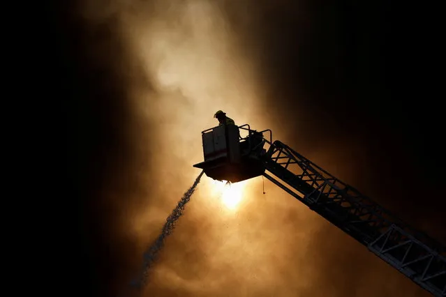 A firefighter works to extinguish a fire at a factory at the industrial park “FINSA II” in Santa Catarina, on the outskirts of Monterrey, Mexico on December 13, 2021. (Photo by Daniel Becerril/Reuters)