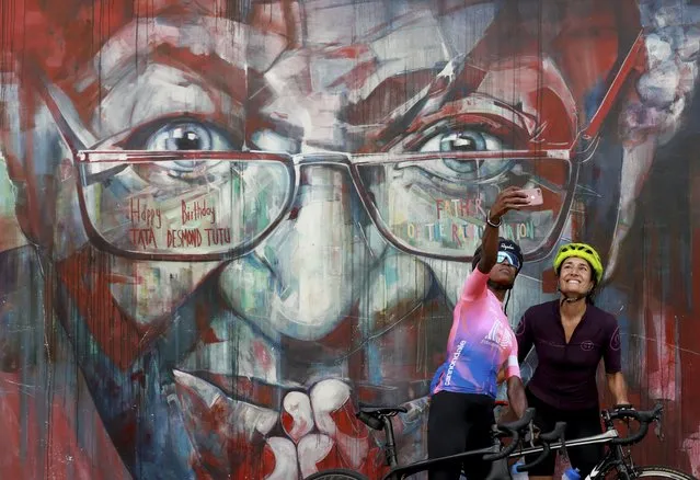 People take selfies at a mural by artist Brian Rolfe depicting the late Anglican Archbishop Emeritus, Desmond Tutu in Cape Town, South Africa, Tuesday, December 28, 2021. The funeral service for Tutu, who died Sunday at the age of 90, will be held on New Years Day. (Photo by Nardus Engelbrecht/AP Photo)