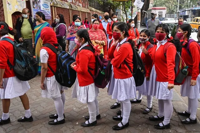 Children queue up to enter the school premises after the schools resumed physical classes which were closed earlier to curb the spread of Covid-19 coronavirus in Kolkata on February 3, 2022. (Photo by Dibyangshu Sarkar/AFP Photo)