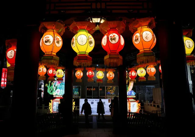 People wearing protective masks, amid the coronavirus disease (COVID-19) outbreak, walk past lantern decoration on Lunar New Year's Eve at China town in Yokohama, Kanagawa Prefecture, Japan, January 31, 2022. (Photo by Kim Kyung-Hoon/Reuters)