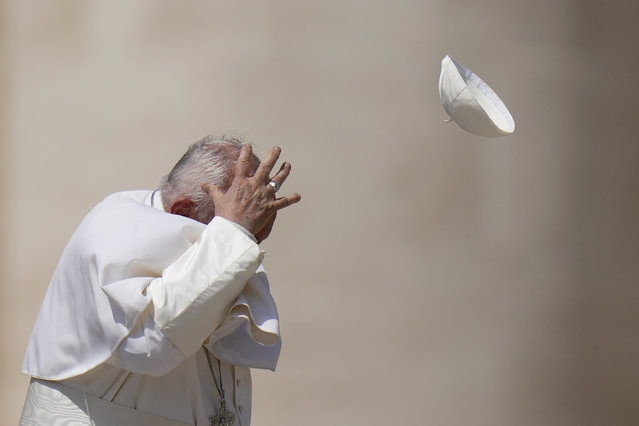 Pope Francis tries to catch his cap as wind blew it away while leaving after his weekly general audience in St. Peter's Square at The Vatican, Wednesday, May 15, 2024. (Photo by Alessandra Tarantino/AP Photo)