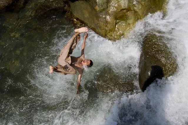 A Kashmiri boy jumps into a stream as boys cool off on a hot afternoon near Wangath, Some 48 kilometers (30 miles) northwest of Srinagar, Indian controlled Kashmir, Sunday, July 5, 2015. (Photo by Dar Yasin/AP Photo)
