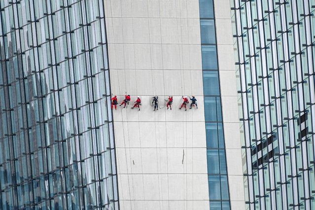 Steeplejack workers secured on safety harness clean the wall of the Marina Bay Sands hotel and resorts building in Singapore on February 1, 2023. (Photo by Roslan Rahman/AFP Photo)