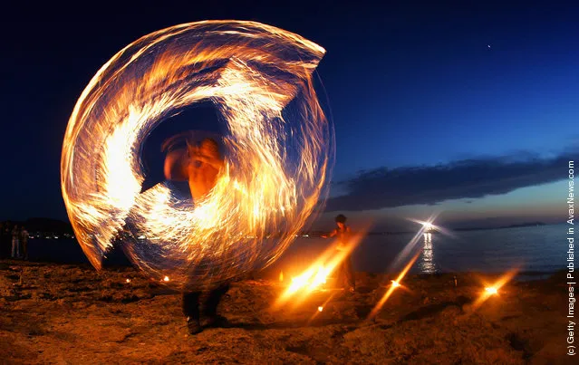 A fire dancer performs for crowds on the beach outside cafe Mambo in San Antonio