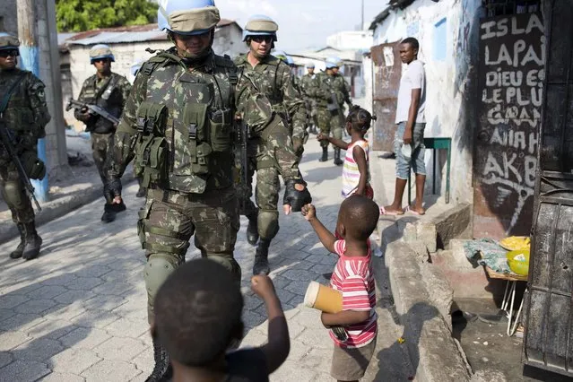 In this February 22, 2017 photo, U.N. peacekeepers from Brazil fist bump with children as they patrol in the Cite Soleil slum, in Port-au-Prince, Haiti. Years of easygoing patrols is a clear sign to many both in Haiti and around the world that it's time to wrap up a U.N. force that's been cycling through this Caribbean country since a 2004 rebellion engulfed Haiti in violence. (Photo by Dieu Nalio Chery/AP Photo)