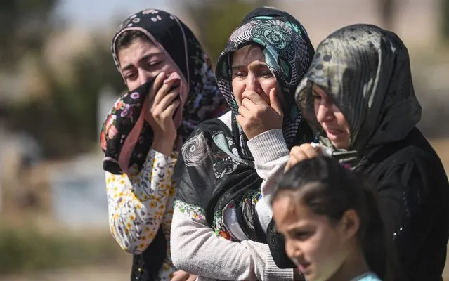 Relatives mourn in front of the grave of Halil Yagmur who were killed in a mortar attack a day earlier in Suruc near northern Syria border, during funeral ceremony in Suruc on October 12, 2019. Ten Turkish civilians were killed in cross-border shelling on Friday, while four of Turkey's soldiers died as Ankara pressed on with its offensive against Kurdish militants in Syria Eight civilians were killed and 35 injured in one mortar strike in Nusaybin in Mardin province, according to the governor's office cited by local media. (Photo by Ozan Kose/AFP Photo)