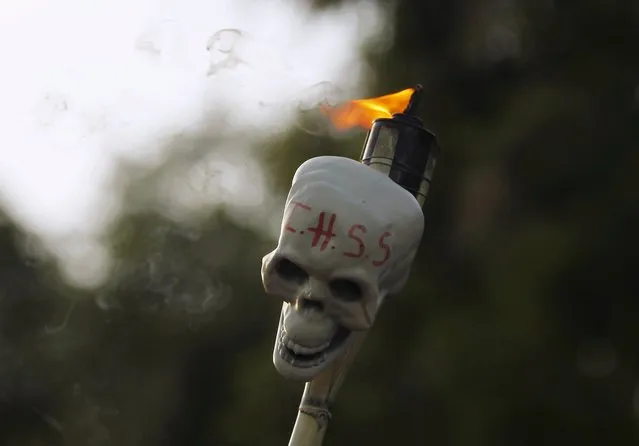 A demonstrator holds a torch with a skull, inscribed with the acronym of the Honduran Institute of Social Security (IHSS), during a march to demand the resignation of Honduras' President Juan Orlando Hernandez in Tegucigalpa July 17, 2015. Thousands Hondurans poured onto the streets of the capital Tegucigalpa on the eighth Friday in a row to demand the resignation of President Juan Orlando Hernandez over a $200 million corruption scandal at the Honduran Institute of Social Security. (Photo by Jorge Cabrera/Reuters)