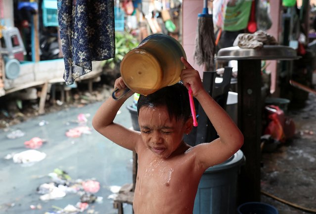 Afghan, 6, pours water on himself as he takes a bath in front of his house at a slum area in Jakarta, Indonesia on July 10, 2024. (Photo by Ajeng Dinar Ulfiana/Reuters)