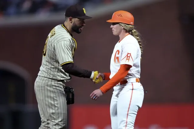 San Diego Padres first baseman Eric Hosmer, left, shakes hands with San Francisco Giants first base coach Alyssa Nakken during the third inning of a baseball game in San Francisco, Tuesday, April 12, 2022. (Photo by Jed Jacobsohn/AP Photo)
