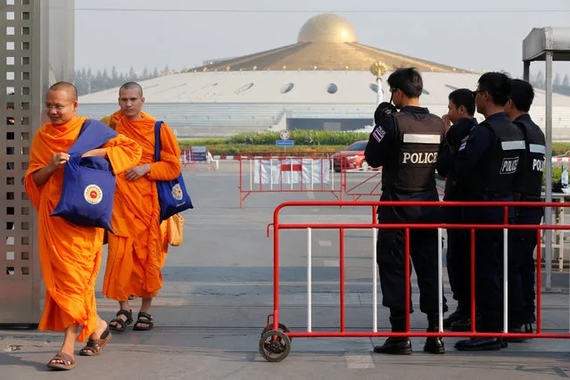 Buddhist monks walk past policemen at Dhammakaya temple in Pathum Thani province, Thailand March 1, 2017. (Photo by Chaiwat Subprasom/Reuters)