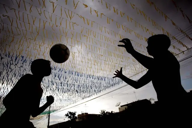 Boys play ball May 23, 2014 in a street decorated for the upcoming World Cup in Brasilia, one of the host cities for the international soccer tournament that starts in June. (Photo by Eraldo Peres/Associated Press)