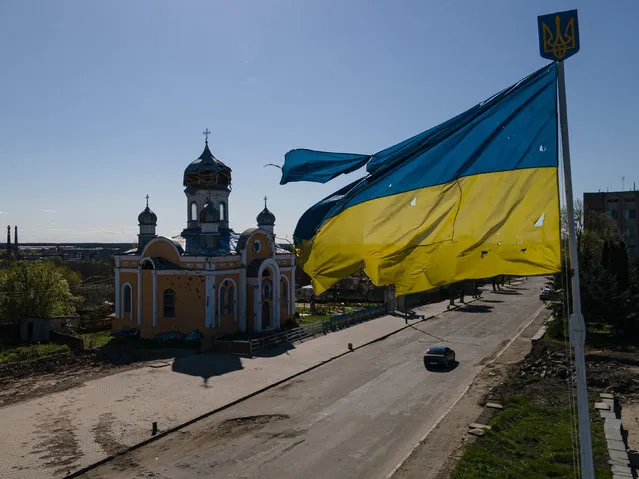 An aerial view shows a damaged St. Godmothers Cover Church next to bullet riddled Ukrainian national flag, on May 4, 2022 in Malyn, Ukraine. The communities north of Kyiv were square in the path of Russia's devastating but ultimately unsuccessful attempt to seize the Ukrainian capital with forces deployed from Belarus, a Russian ally. (Photo by Alexey Furman/Getty Images)