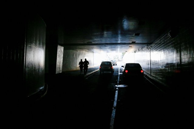 People walk through a dark tunnel during a power outage affecting Caracas and other regions of the country, in Caracas, Venezuela on August 30, 2024. (Photo by Leonardo Fernandez Viloria/Reuters)