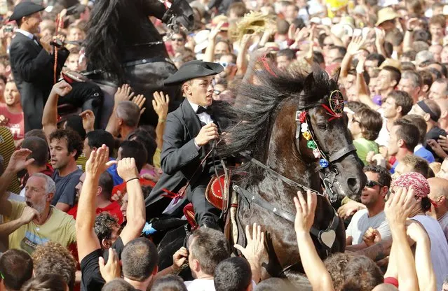 Horses rear as their drivers urge them through a cheering crowd during the traditional Festival of St. John in downtown Ciutadella, on the Spanish Balearic Island of Menorca, on June 23, 2014. The riders represent ancient Ciutadella society. (Photo by Enrique Calvo/Reuters)