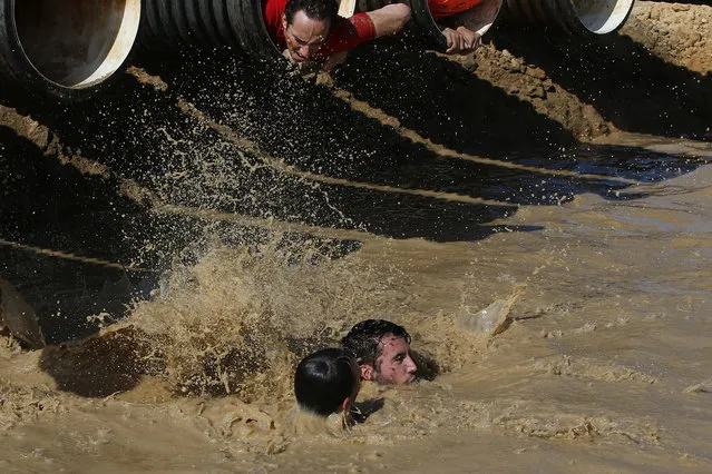 Participants swim in a mud pool during the Mud Day athletic event at El Goloso Military base on the outskirts of Madrid, Spain, Saturday, June 11, 2016. (Photo by Paul White/AP Photo)