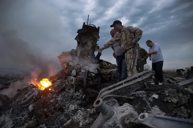 In this Thursday, July 17, 2014 file photo, people inspect the crash site of a passenger plane near the village of Grabovo, Ukraine. Any suspects in the downing of Malaysia Airlines flight 17 over Ukraine in 2014 will be prosecuted in the Netherlands, the Dutch government announced Wednesday July 5, 2017. (Photo by Dmitry Lovetsky/AP Photo)