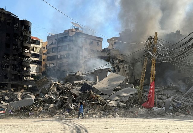 A woman walks past damaged buildings and debris in the aftermath of a strike, amid ongoing hostilities between Hezbollah and Israeli forces, in Beirut’s southern suburbs, Lebanon on October 3, 2024. (Photo by Mohamed Azakir/Reuters)