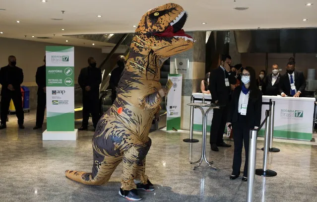 A demonstrator wearing a dinosaur costume protests against an auction of exploratory offshore oil blocks in the Campos, Santos, Pelotas and Potiguar basins, which draws interest from oil majors including Chevron, Shell, Total and Petrobras, in Rio de Janeiro, Brazil, October 7, 2021. (Photo by Ricardo Moraes/Reuters)