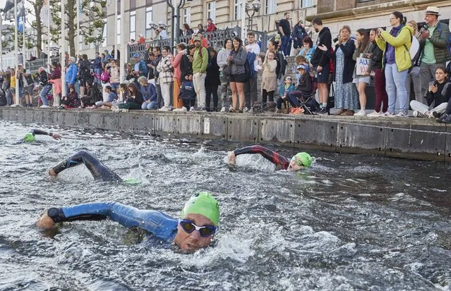 Spectators watch athletes swimming in the Kleine Alster during the Ironman triathlon in Hamburg, Germany on Sunday, June 5, 2022. (Photo by Georg Wendt/dpa via AP Photo)